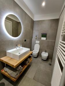 a bathroom with a sink and a toilet and a mirror at La Morra Apartments in La Morra