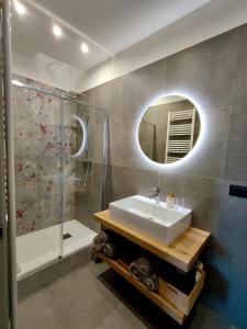 a bathroom with a sink and a shower and a mirror at La Morra Apartments in La Morra