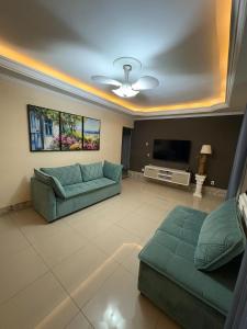 a living room with a couch and a tv at Casa com piscina in São Pedro da Aldeia