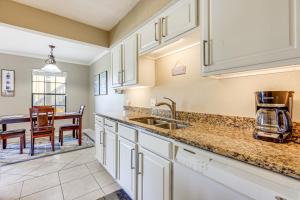 a kitchen with white cabinets and a dining room at Walk to St Augustine Beach! Condo with Pool Access in Saint Augustine Beach