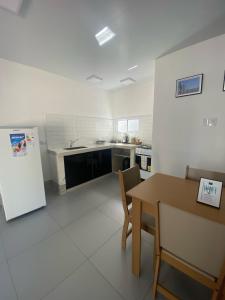 a white kitchen with a table and a refrigerator at Steves House Flat Hotel in Puerto Iguazú +4 photos