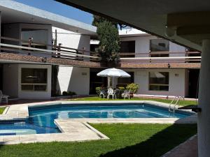 a swimming pool in front of a house with an umbrella at Hotel Quinta Rivera in Actopan