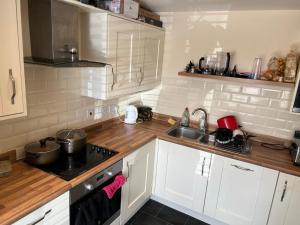 a kitchen with white cabinets and a sink and a stove at Butter row in Wolverton