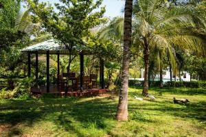a gazebo in a yard with palm trees at The Peacock Village Eco Resort & Spa in Amrutūr