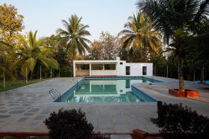 a house with a swimming pool and palm trees at The Peacock Village Eco Resort & Spa in Amrutūr