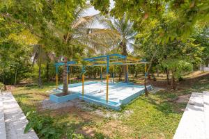 an empty playground in a park with trees at The Peacock Village Eco Resort & Spa in Amrutūr