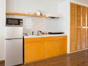 a kitchen with a white refrigerator and wooden cabinets at Garden Palace Downtown Koror in Koror