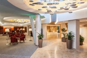 a lobby with tables and chairs in a building at Ensana Thermal Aqua in Hévíz