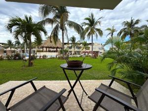 - une table et deux chaises sur une terrasse avec des palmiers dans l'établissement Villa Tostados Acapulco Diamante, à Acapulco