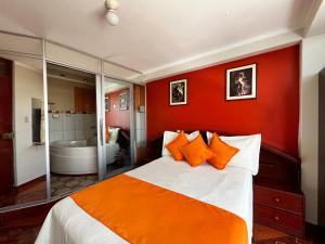 a bedroom with orange walls and a bed with orange pillows at Hostal Bryan in Tacna