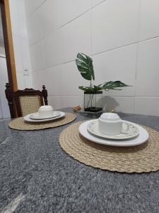 two plates and cups on top of a table at Apê 03 - confortável e perto de tudo in Vitória da Conquista