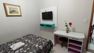 a room with a bed and a desk and a tv at Apê 03 - confortável e perto de tudo in Vitória da Conquista +2 photos
