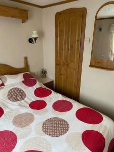 a bedroom with a bed with a red and white comforter at Lovely 2 bedroomed Caravan on Edwards Towyn in Kinmel Bay