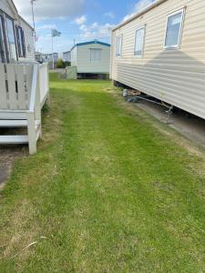 an empty yard next to a mobile home at Lovely 2 bedroomed Caravan on Edwards Towyn in Kinmel Bay