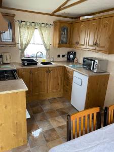 a kitchen with wooden cabinets and a white refrigerator at Lovely 2 bedroomed Caravan on Edwards Towyn in Kinmel Bay