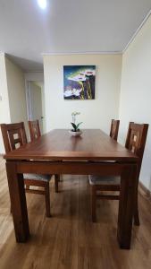 una mesa de comedor de madera con sillas y una pintura en Departamentos Hometainer, en Santiago