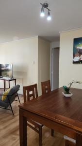 Un comedor con mesa y sillas de madera. en Departamentos Hometainer, en Santiago