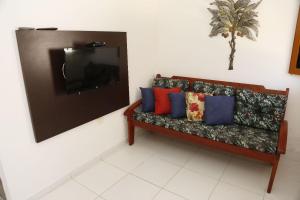 a couch in a room with a tv on a wall at Tamandaré Residence Beach 2 in Tamandaré