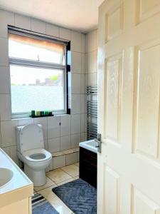 a bathroom with a toilet and a sink and a window at MASTER Bedroom in Feltham