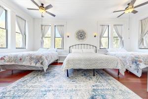 two beds in a white room with windows at The Tree House in Buxton