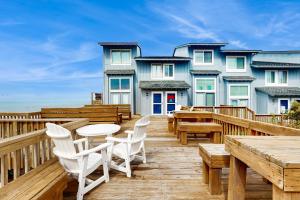 a deck with wooden tables and chairs and a building at Ocean Glen 12 in Pine Knoll Shores