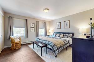 a bedroom with a bed and a chair and two windows at Kindred Hollow in Ludlow