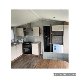 eine kleine Küche mit weißen Schränken und einem grauen Sofa in der Unterkunft 3 bedroomed CH Caravan on Presthaven Beach Resort in Talacre