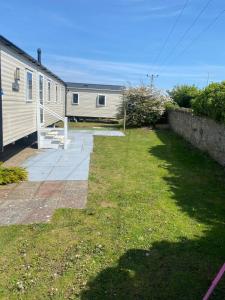 ein leerer Hof neben einem Haus mit einem Zaun in der Unterkunft 3 bedroomed CH Caravan on Presthaven Beach Resort in Talacre