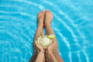 a person holding a drink in front of a pool at Relais Villa Olivi in Costermano sul Garda