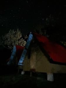 a small house with a red roof at night at Hostel el molle capulichayoc in Santa Teresa