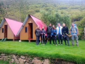 a group of people standing in front of a small house at Hostel el molle capulichayoc in Santa Teresa