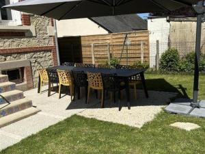 ein schwarzer Tisch und Stühle unter einem Schirm in der Unterkunft Charmant Gîte Familial avec Jardin Privatif et Confort Moderne, au Cœur de la Touraine - FR-1-381-550 in Sepmes