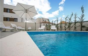 a swimming pool with a umbrella and chairs and a table at 1 Bedroom Lovely Apartment In Vrsi in Vrsi +7 photos