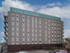 a hotel routine inn with cars parked in a parking lot at Hotel Route-Inn Koga Ekimae in Koga