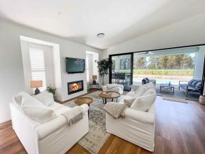 a living room with white furniture and a fireplace at Florette's Pool Suite in Pokolbin