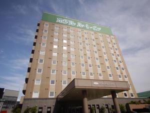 a large building with a sign on top of it at Hotel Route-Inn Omagari Ekimae in Daisen