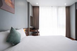 1 dormitorio con cama blanca y almohada verde en Eden Hue Hotel, en Hue