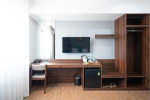Habitación con escritorio y TV en la pared. en Eden Hue Hotel, en Hue