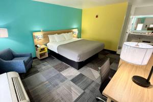 ニスビルにあるDays Inn by Wyndham Eglin AFBのベッドと椅子付きのホテルルーム
