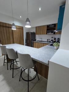 a kitchen with a counter with chairs around it at Descanso en ACAPULCO DIAMANTE in Acapulco