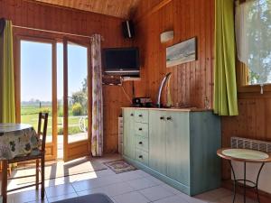 une cuisine avec un meuble, une télévision et une fenêtre dans l'établissement Chalet authentique près de la plage pour 6 personnes - FR-1-788-65, à Merville-Franceville-Plage