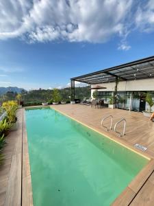 einem großen Pool mit Holzterrasse und einem Gebäude in der Unterkunft Acogedor apartamento en Santa Rosa de Cabal in Santa Rosa de Cabal
