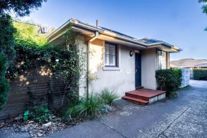 una piccola casa con un portico e una panchina rossa di 2BR Elsternwick Escape with Courtyard a Melbourne