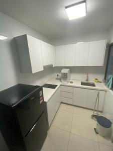 a kitchen with a black refrigerator and white cabinets at Tulip Residence Elmina in Shah Alam