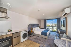 a bedroom with a bed and a kitchen with a balcony at Marsden Suites Albany in Albany