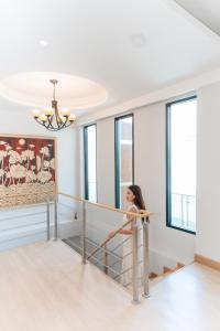 a woman standing on a railing in a room with windows at PureLux6 - 3BR Pool Villa in Chiang Mai