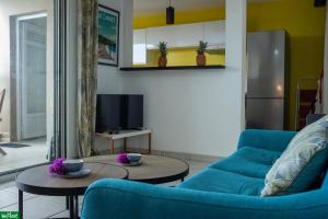 un salon avec un canapé bleu et une télévision dans l'établissement Moutte - Superbe appartement pour deux, à Fort-de-France