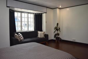 a bedroom with a bed and a couch and a window at Balai Modern Home in Baguio