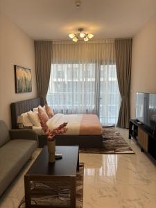 a bedroom with a bed and a couch and a tv at Dream F1 Airport Studio Pool & Gym in Abu Dhabi