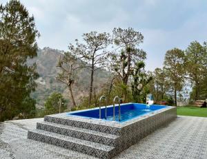 an outdoor swimming pool with a set of concrete steps and a swimming poolvisorvisor at The Lalita's Majestic Pines in Kasauli